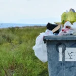 Ein überfüllter Müllcontainer, der mit verschiedenen Abfällen und Plastiktüten gefüllt ist.